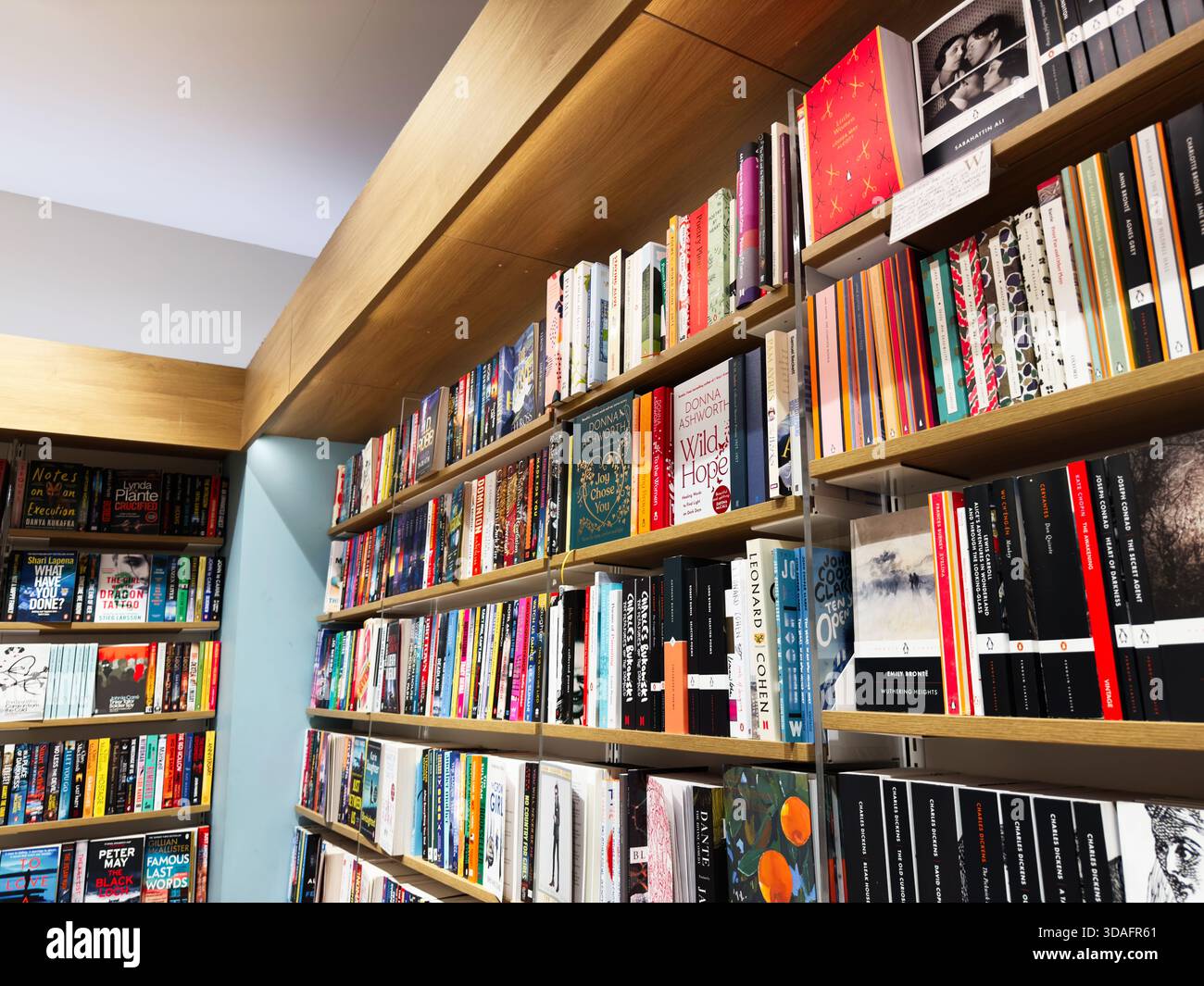 Manchester, Regno Unito - 15 novembre 2025: Scaffali luminosi e invitanti ospitano diversi libri, creando un'atmosfera accogliente e colorata da libreria. Foto Stock
