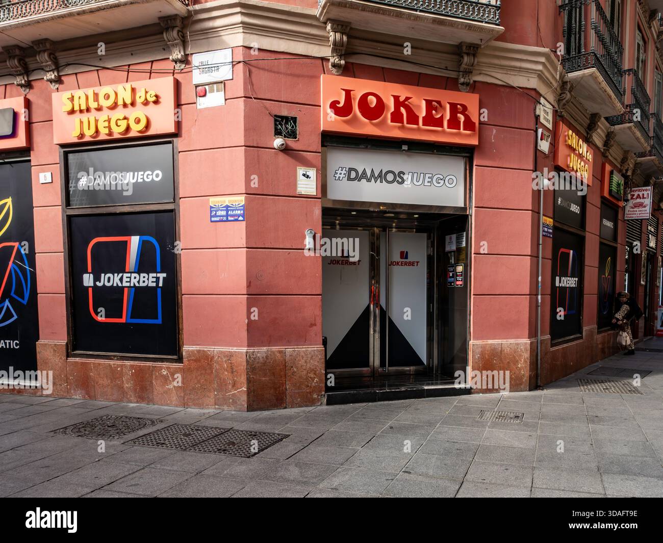Sala giochi Jokerbet/Joker ed esterno "Salón de Juego". Malaga, Spagna, edificio d'angolo, Calle Cisneros. Negozio di scommesse, cartellonistica arancione brillante. Foto Stock