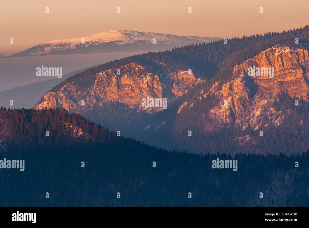 Veduta aerea delle scogliere scoscese baciate dal sole e delle cime innevate, che contrastano nettamente con le profonde ombre dei pendii boscosi, Malino Brdo, Foto Stock