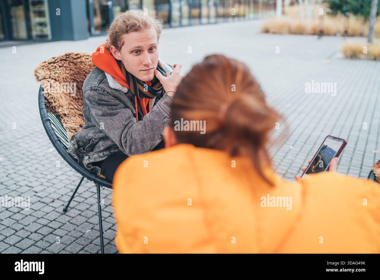 Madre con un figlio adulto seduto su una terrazza all'aperto in un bar, bevendo un caffè e facendo una bella conversazione. Mamma mostra contenuti interessanti su Foto Stock