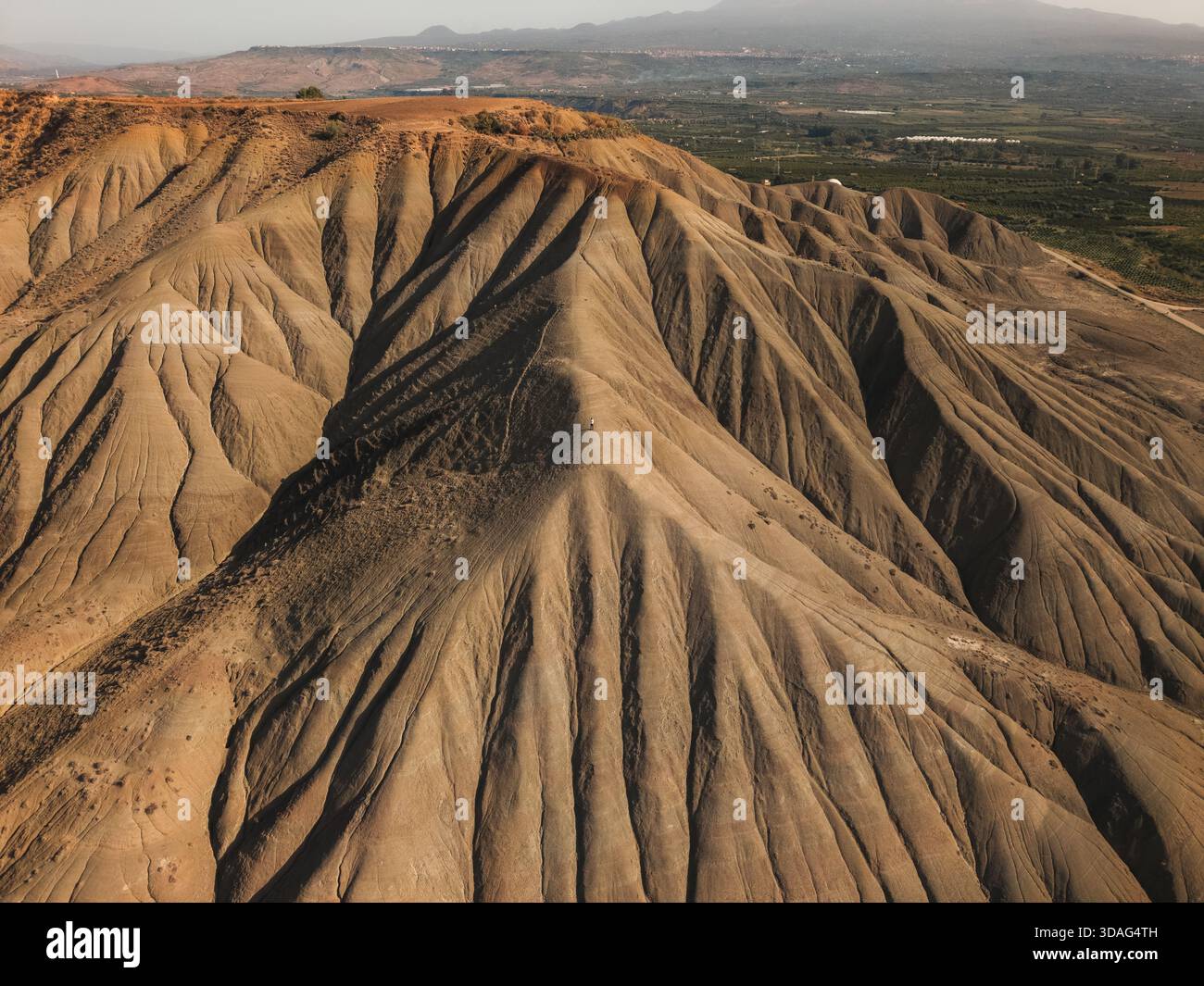 Vista aerea della crosta terrestre che si innalza in formazioni strutturate contro un orizzonte nebbioso, scolpito da luce e ombra, Centuripe, Sicilia, Italia. Foto Stock