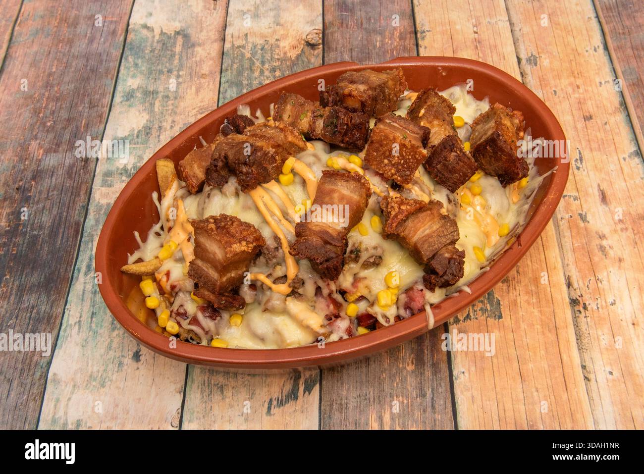 Un piatto di legno con una generosa porzione di torreznos in stile Soria (pancetta di maiale croccante), croccante all'esterno e succoso all'interno, appena fritto e. Foto Stock
