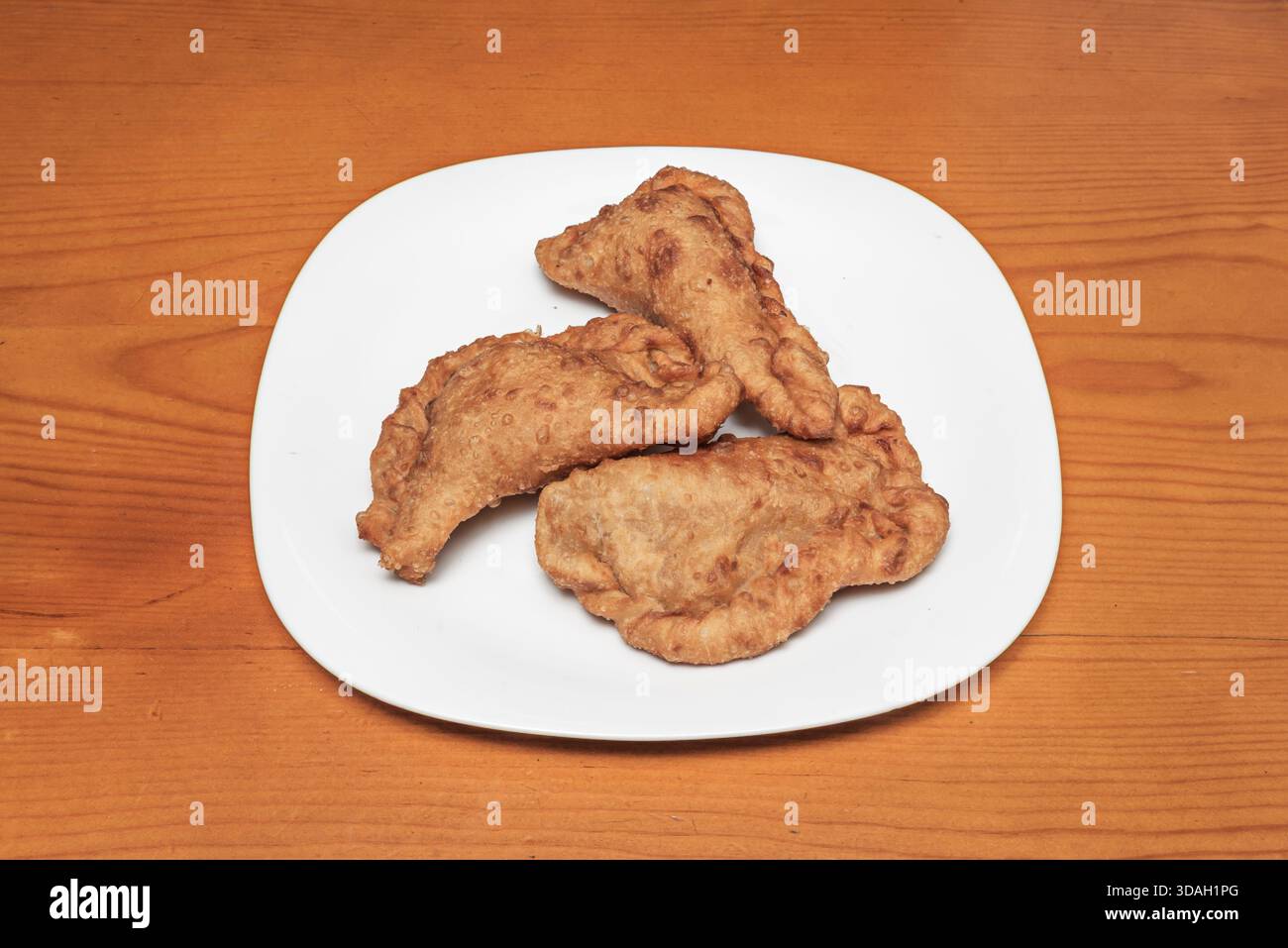 Diverse grandi empanadas al forno, con impasto croccante e il caratteristico bordo ondulato, rivelando il loro ripieno di tonno, pepe e pomodoro Foto Stock