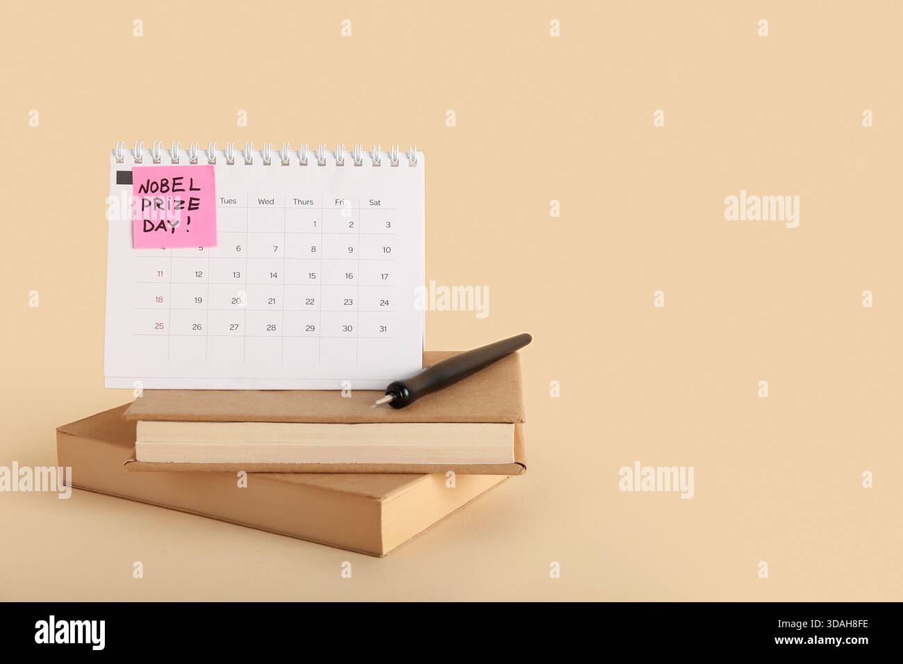 Calendario con testo GIORNATA PREMIO NOBEL e libri su sfondo beige Foto Stock