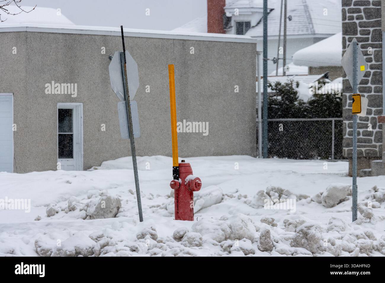 Canada, Quebec, 30 novembre 2025: L'idrante rosso del fuoco si erge tra la neve, circondato da cartelli pendenti Foto Stock