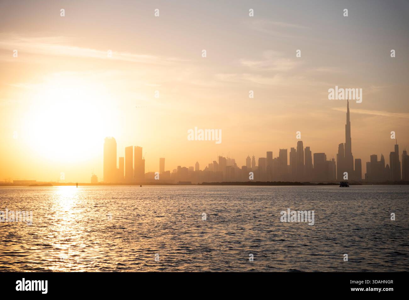 Vista cinematografica dello skyline di Dubai al tramonto con il Burj Khalifa e il tranquillo lungomare Foto Stock