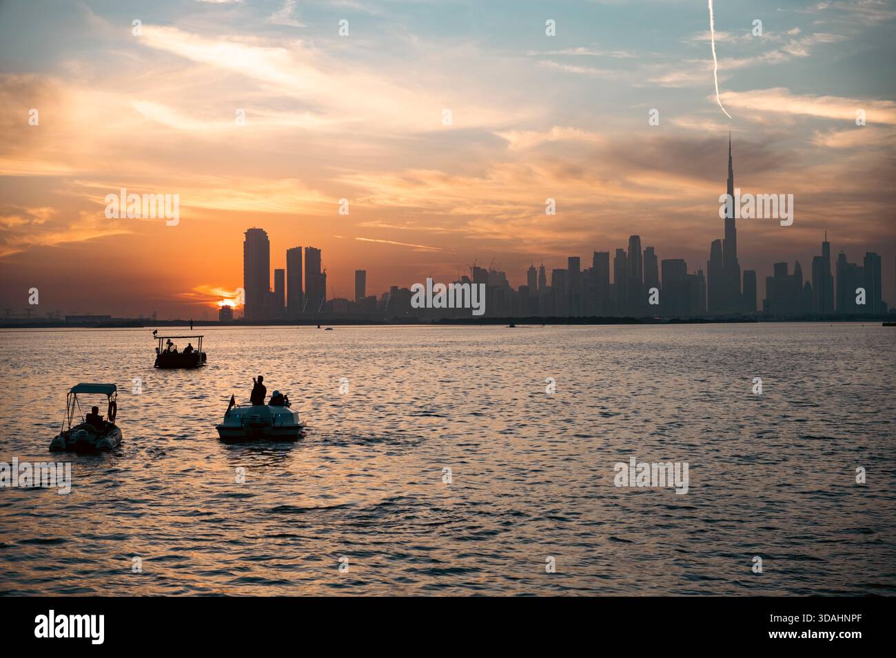 Skyline di Dubai al tramonto con Burj Khalifa e barche sull'acqua con turismo di lusso sul lungomare, paesaggio urbano moderno e destinazione invernale di tendenza 2026 Foto Stock