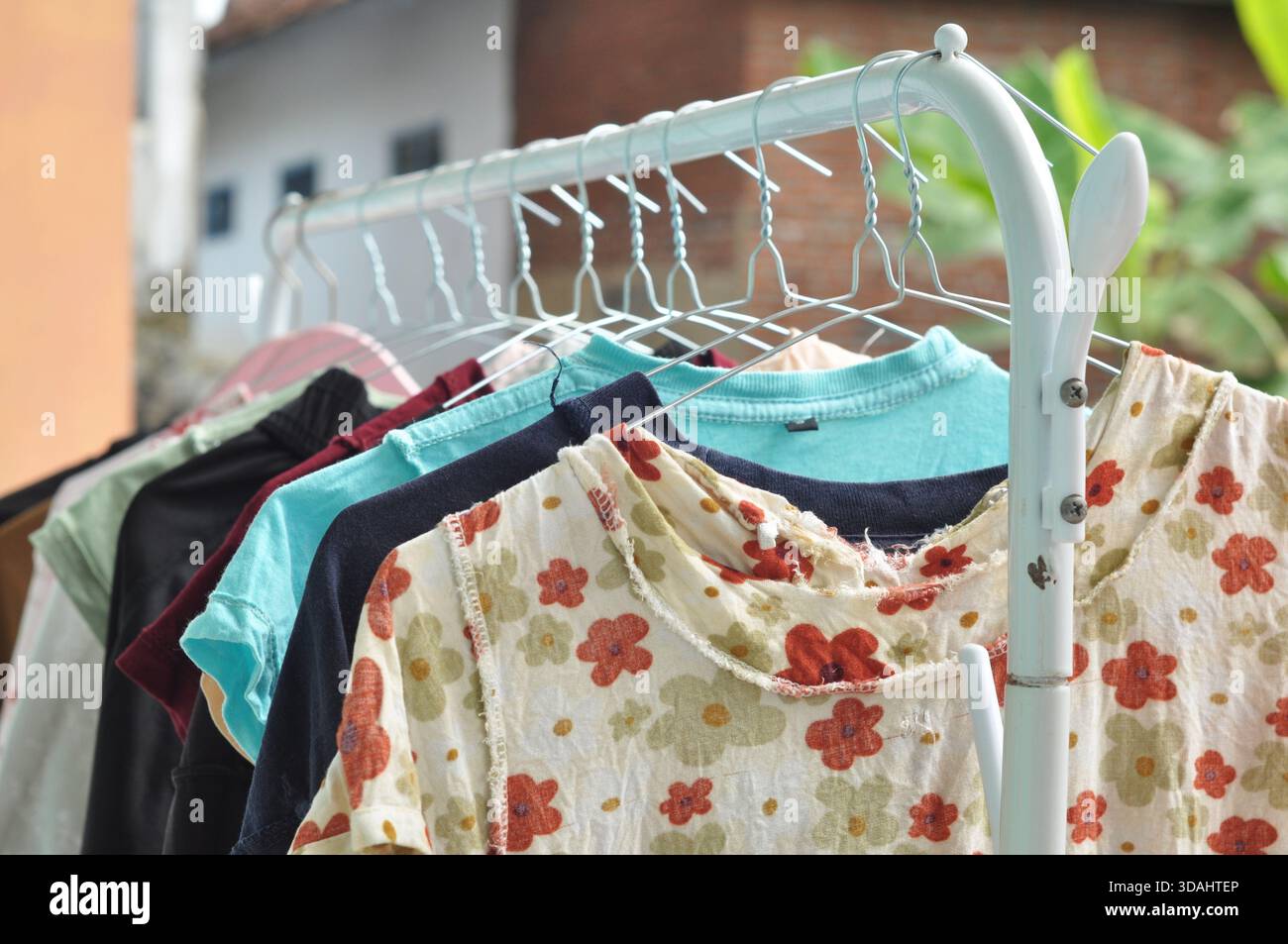 Vestiti colorati appesi al rack di asciugatura per esterni con luce naturale Foto Stock