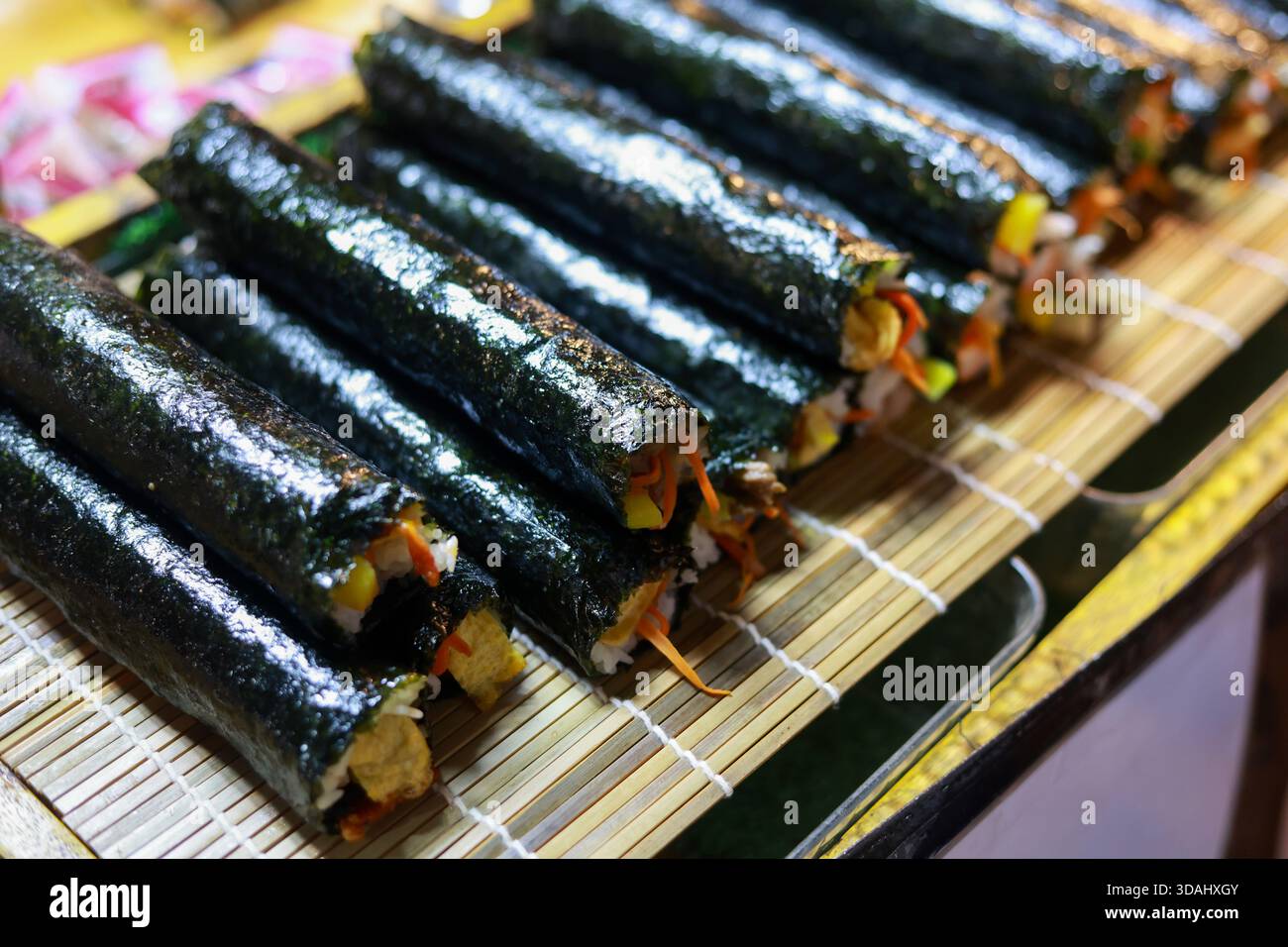 Deliziosi panini kimbap coreani freschi in mostra. Tradizionale cibo gimbap a base di alghe e riso, per creare uno spuntino o un pasto appetitoso su un tappetino di bambù Foto Stock