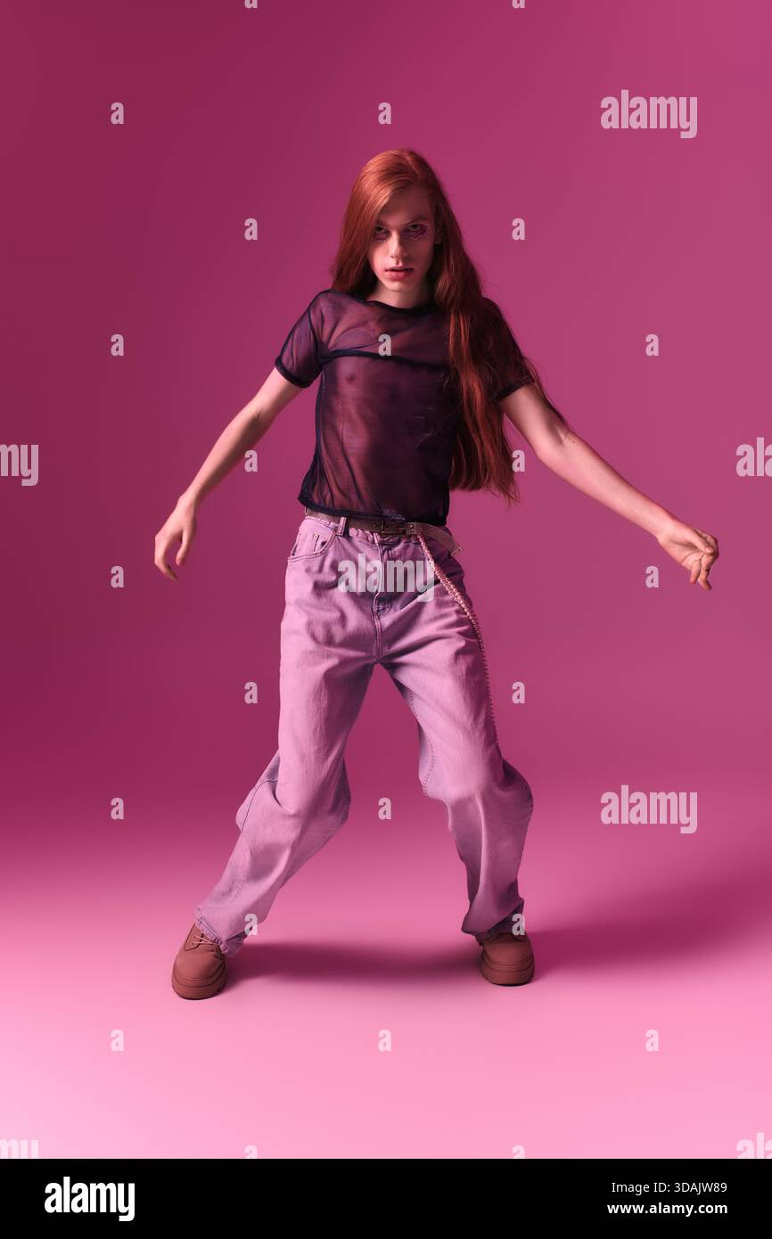 Una persona balla gioiosamente su uno sfondo rosa brillante, mostrando i loro veri colori. Foto Stock