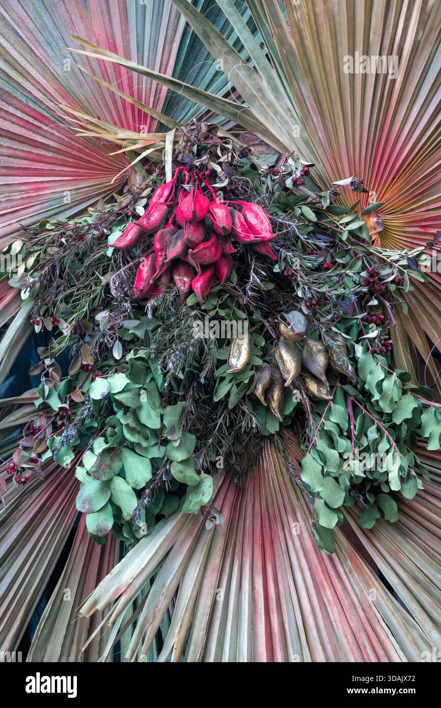 Fondo astratto e strutturato di una composizione floreale essiccata. Presenta grandi fronde delle palme radianti in colori sbiaditi, contrapposte a gruppi centrali Foto Stock