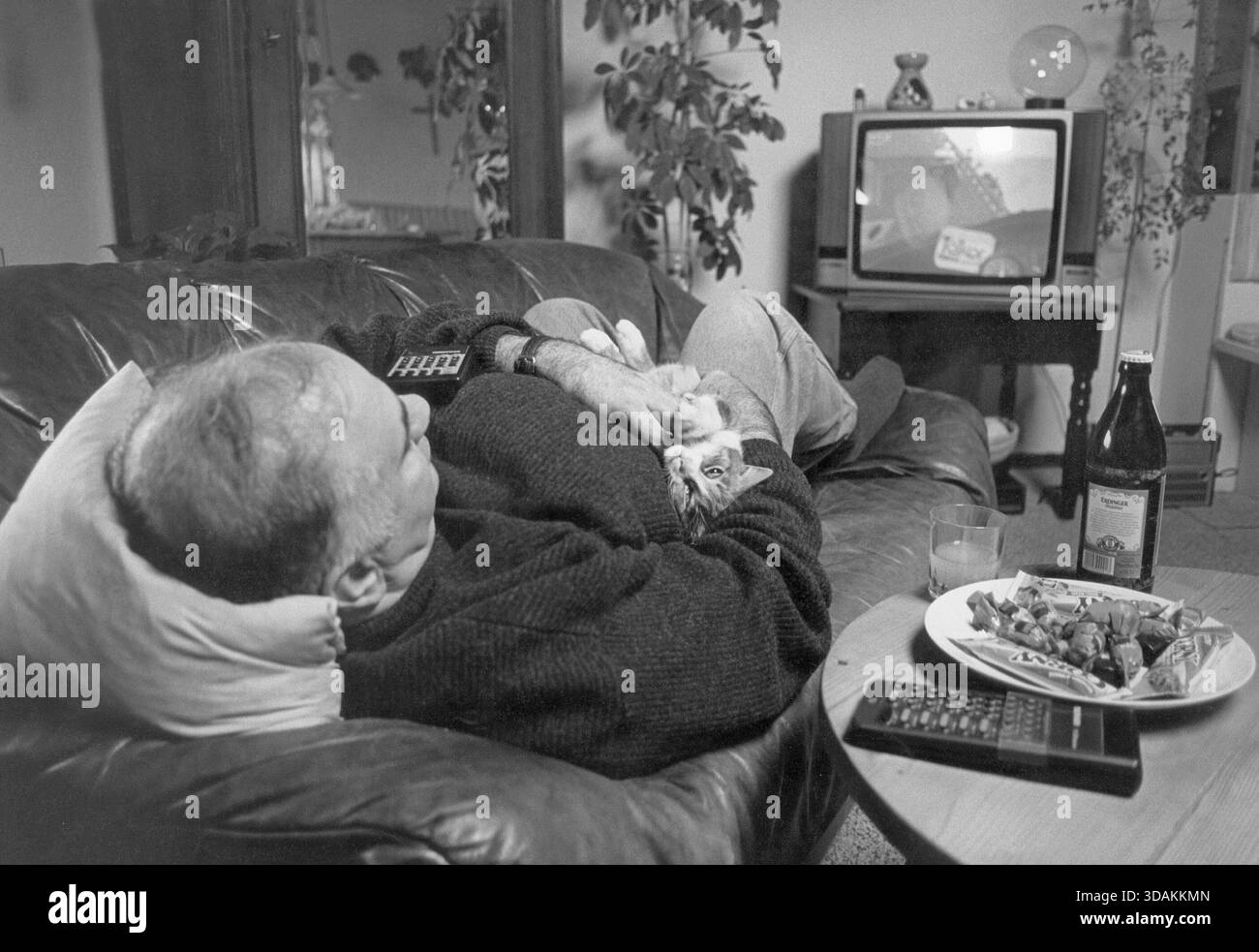 Un uomo è sdraiato sul divano a guardare la TV. [traduzione automatizzata] Foto Stock