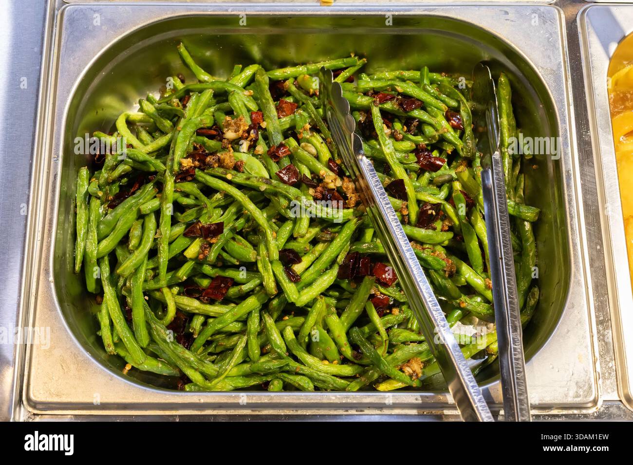 Vista ravvicinata di un piatto a fagioli verdi appena cucinati conditi con peperoncino e aglio secchi, pronti per essere serviti Foto Stock