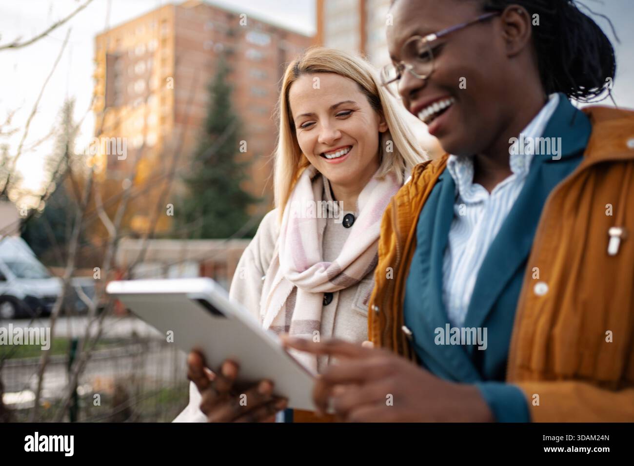 Diverse donne e colleghi che collaborano su un tablet digitale all'aperto Foto Stock