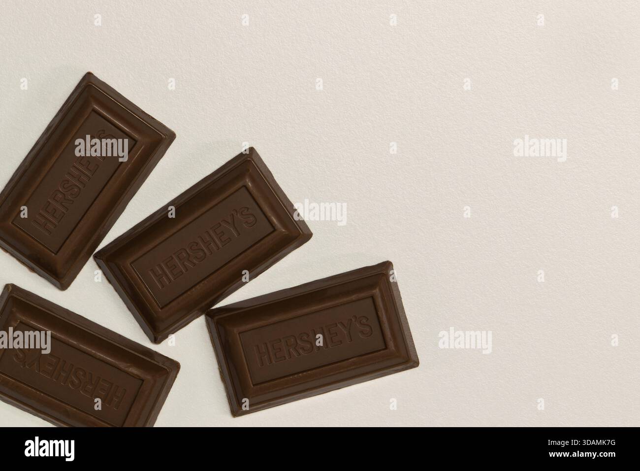 Houston, Texas Stati Uniti d'America 12-10-2025: Quadrati di cioccolato al latte a zucchero zero Hersheys sparsi su uno spazio di copia su sfondo bianco. Foto Stock
