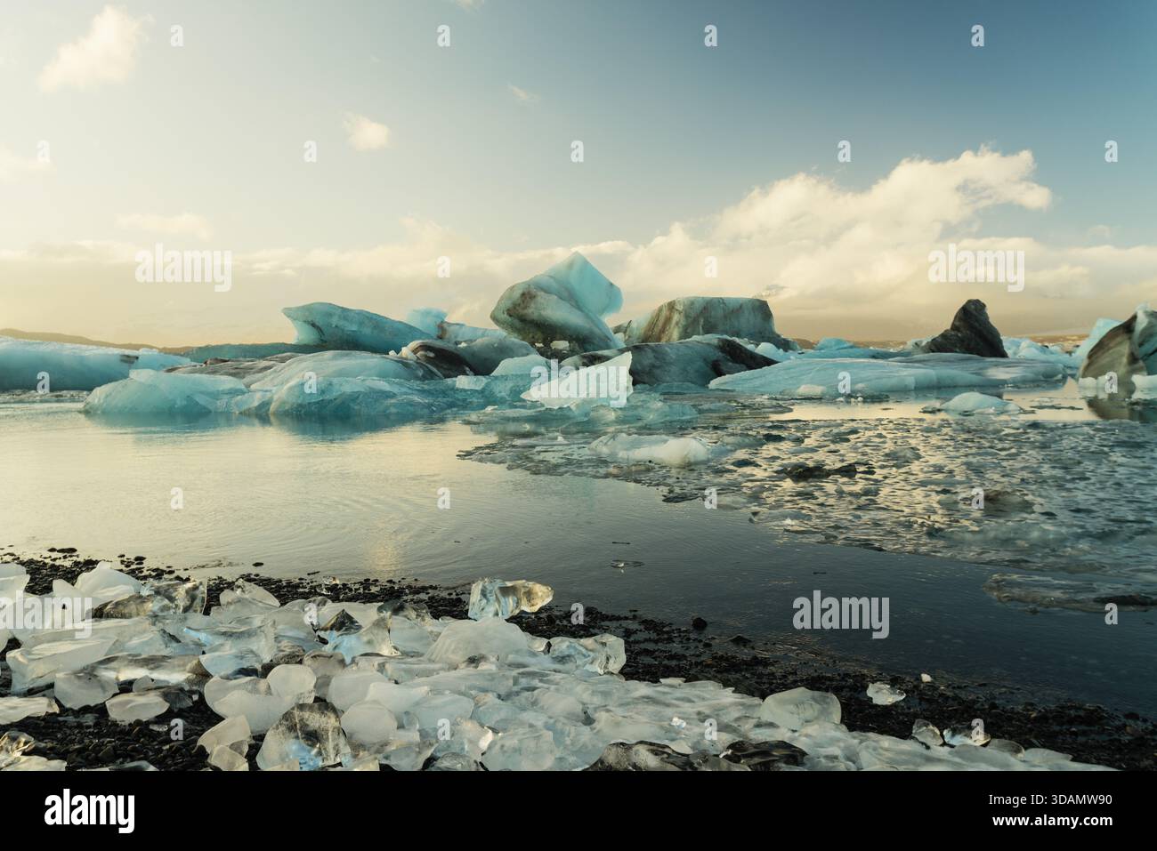 Vista della tranquilla laguna del ghiacciaio punteggiata da scintillanti iceberg che riflettono la luce soffusa del giorno a Jokulsarlon, Sveitarfelagid Hornafjordur, Islanda. Foto Stock