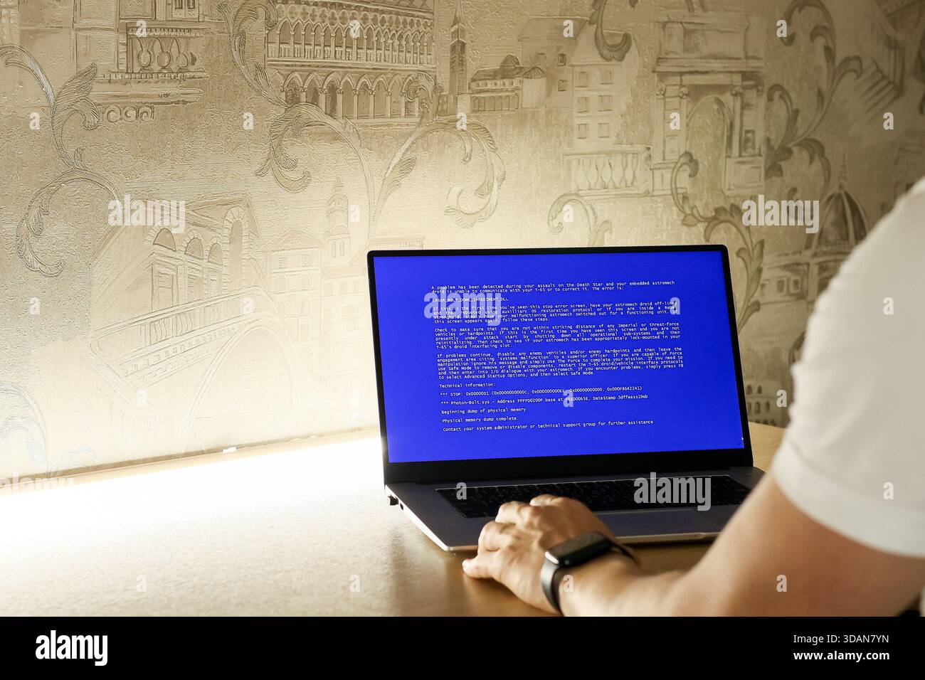 Primo piano di digitazione delle dita sulla tastiera mentre lo schermo mostra un errore critico di sistema in blu Foto Stock