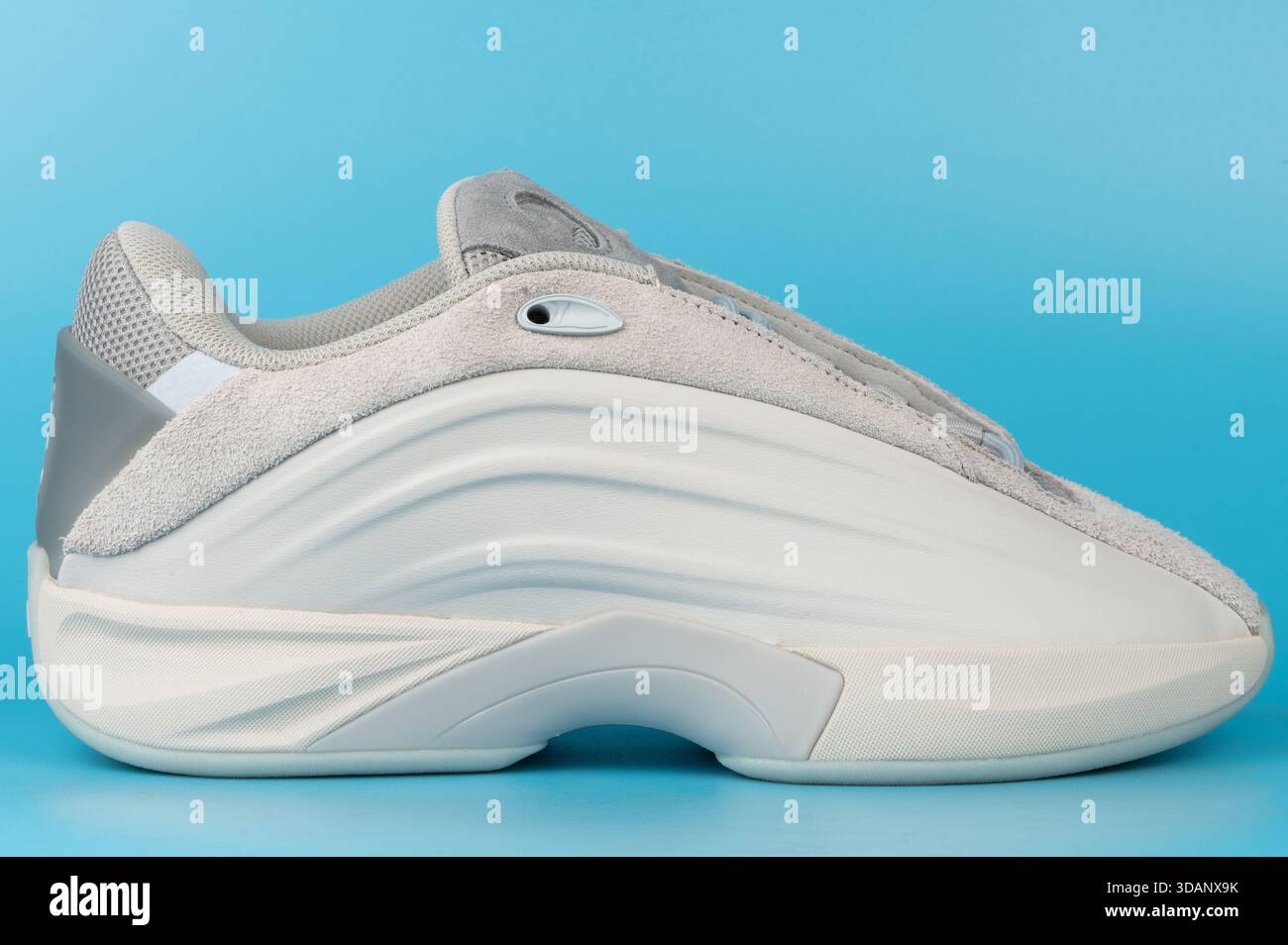 Sneaker visualizzata su uno sfondo blu che ne mostra il lato. È dotato di una combinazione di materiali in colori chiari. Foto Stock