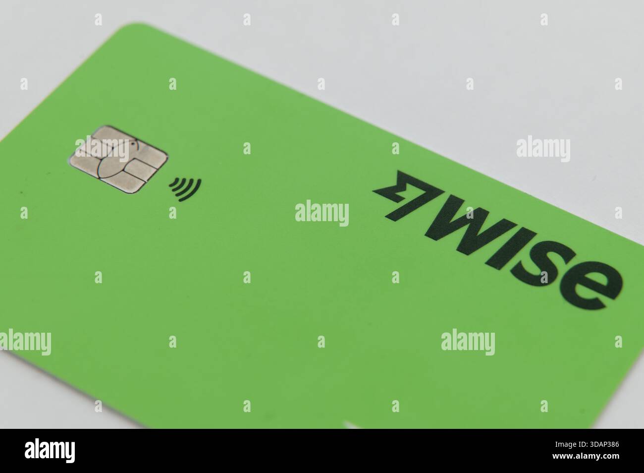 Primo piano del chip di carta Wise e del simbolo di pagamento contactless su una superficie verde brillante. Foto Stock