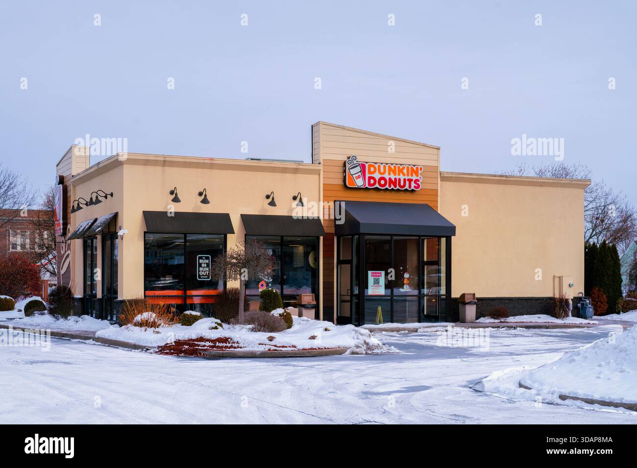 Utica, NY - 9 dicembre 2025: A Winter Snow view of Dunkin' '(ex Dunkin' Donuts), è una catena globale di fast-service specializzata in caffè, ciambelle, e. Foto Stock