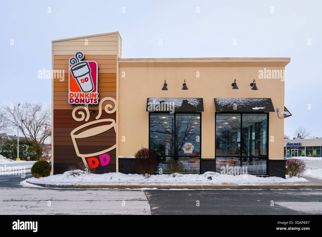 Utica, NY - 9 dicembre 2025: A Winter Snow view of Dunkin' '(ex Dunkin' Donuts), è una catena globale di fast-service specializzata in caffè, ciambelle, e. Foto Stock