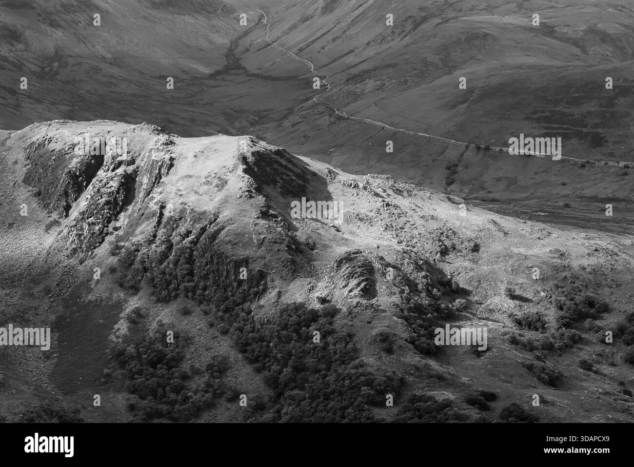 Paesaggio bianco e nero di Snowdonia con ripide strati, spettacolare copertura nuvolosa e luce solare che si irrompe per illuminare la valle e le pendici Foto Stock