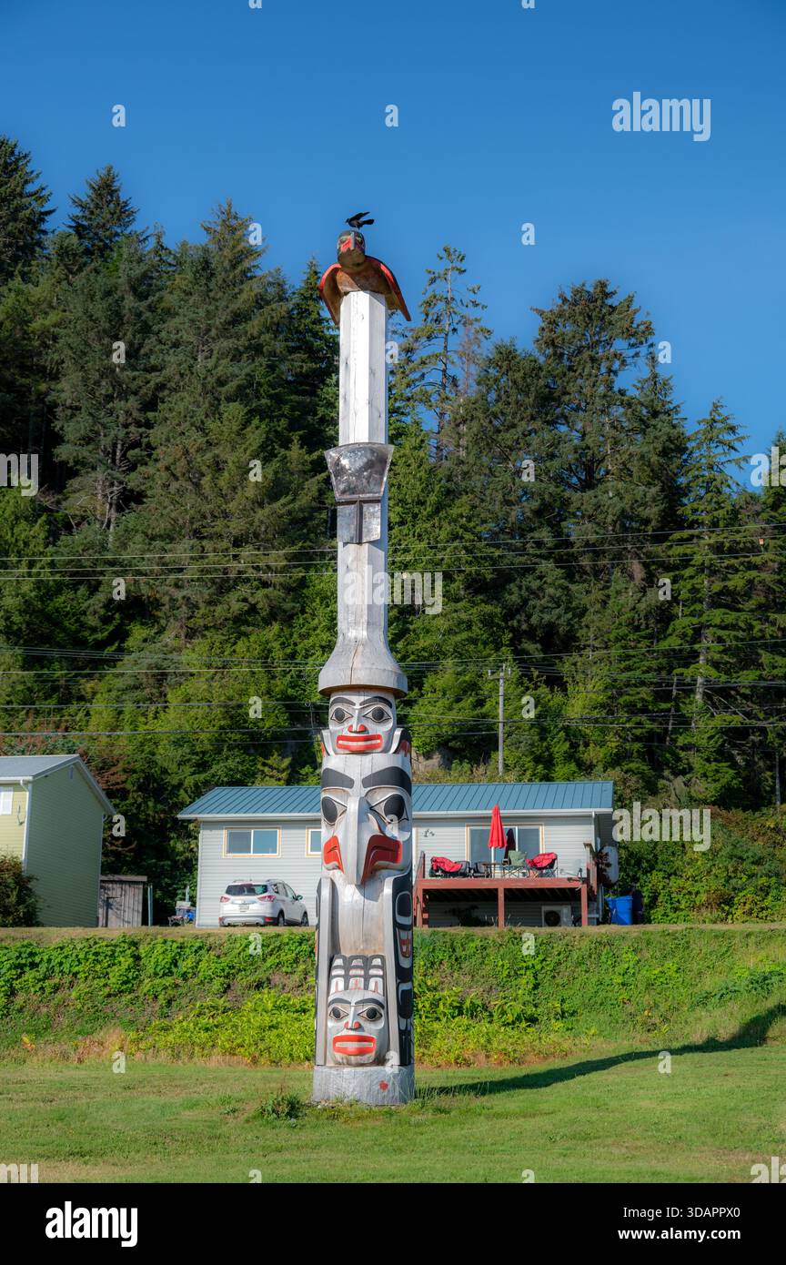 Un corvo vivo appollaiato sulla figura del corvo scolpito in cima al Polo di Bill Reid Unity a Skidegate. Foto Stock