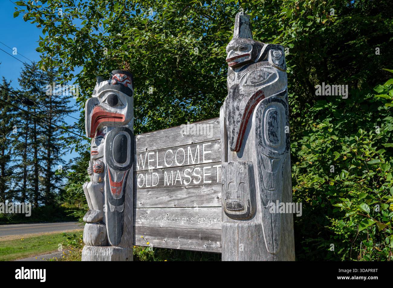 Il cartello "Welcome to Old Massett", che presenta la tradizionale arte Haida formline, segna la porta d'ingresso alla storica comunità indigena. Foto Stock