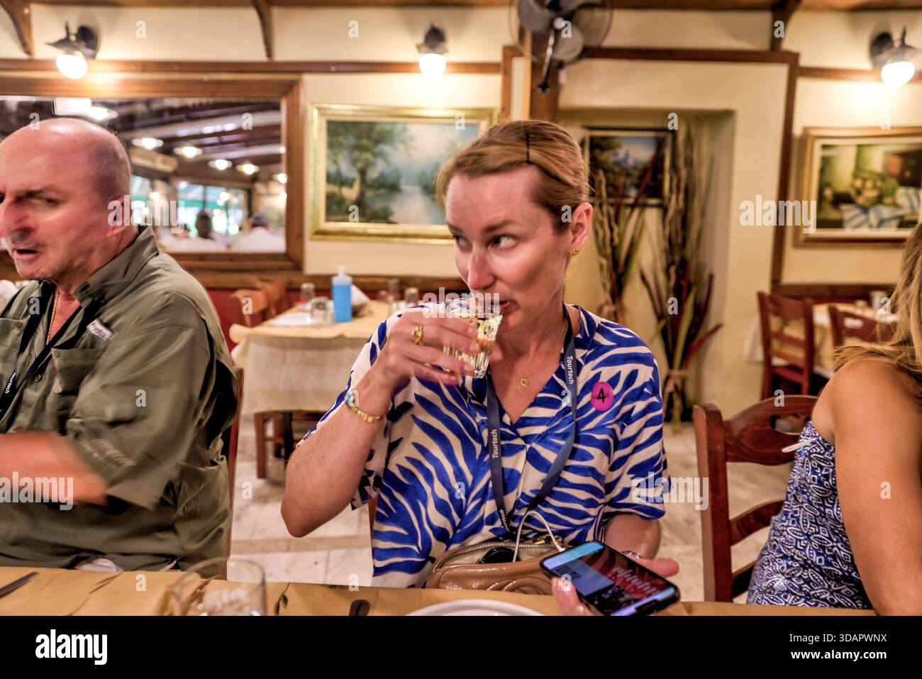 Donna che assaggia vino all'interno di un ristorante greco tradizionale a Sounion, Grecia, catturando la cultura culinaria locale e i momenti di viaggio rilassati. Foto Stock