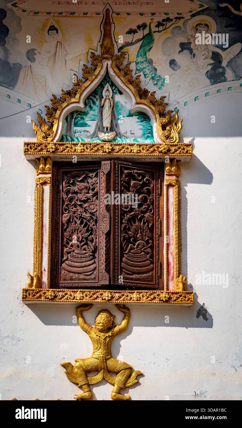 Finestra ornata in legno con intricati intagli e cornice dorata su una parete del tempio. Foto Stock