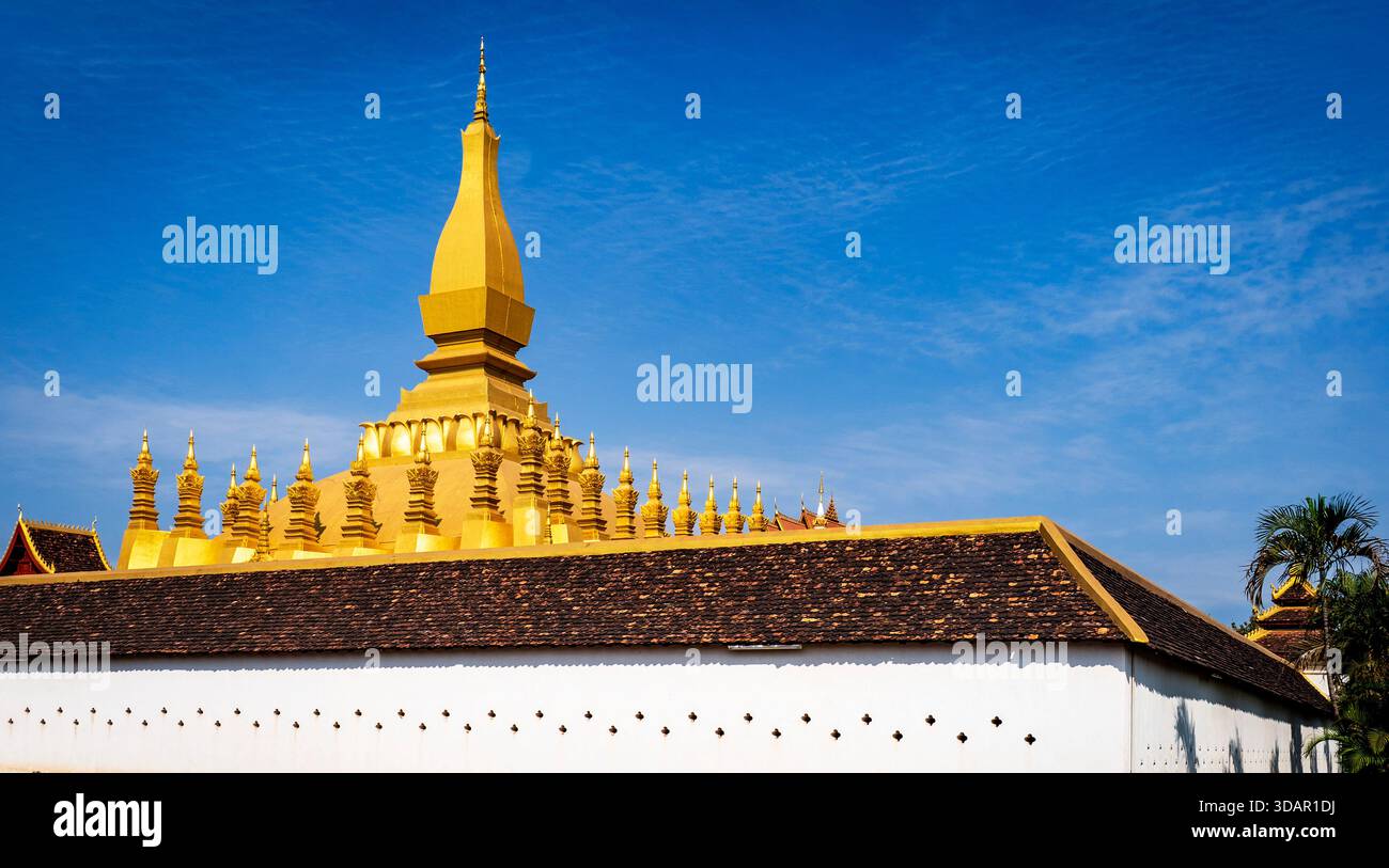 Stupa buddhista dorato contro un cielo blu con mura circostanti. Foto Stock