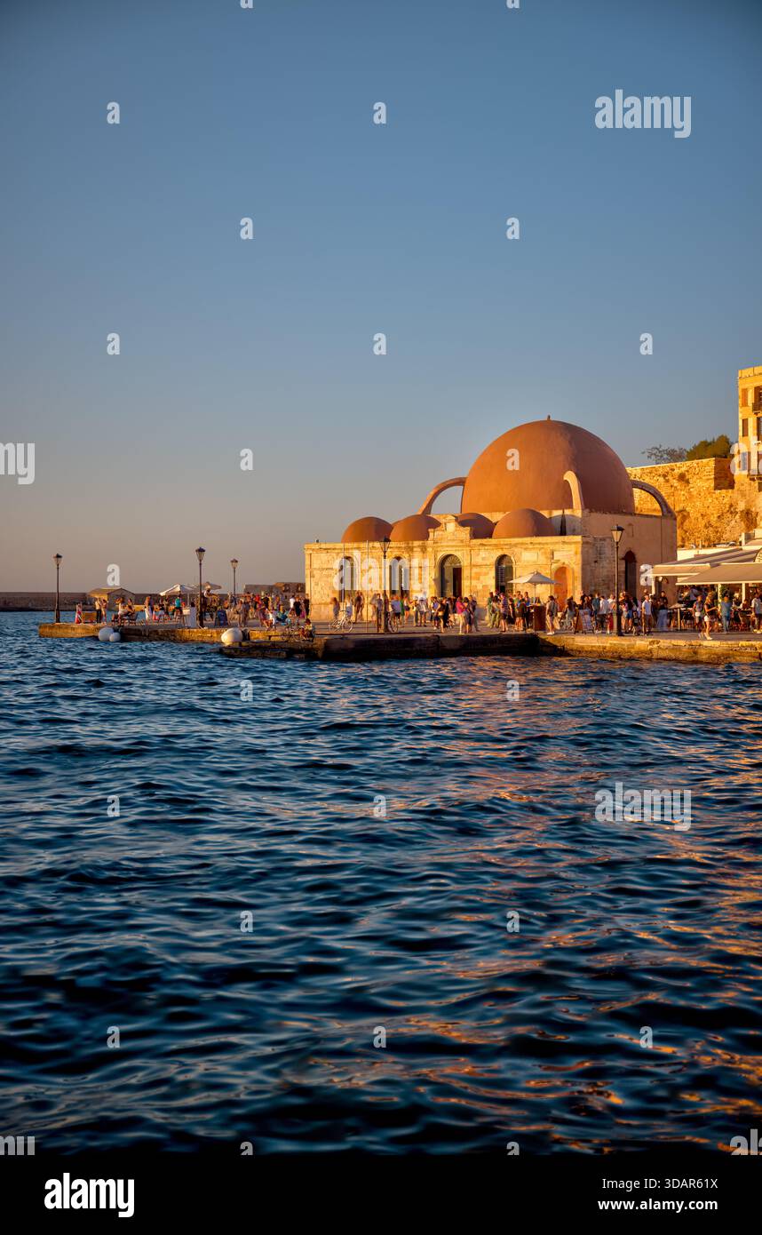 Vista dell'ora d'oro del porto veneziano e della moschea di Hassan Pasha lungo il lungomare di Chania, Creta. Foto Stock