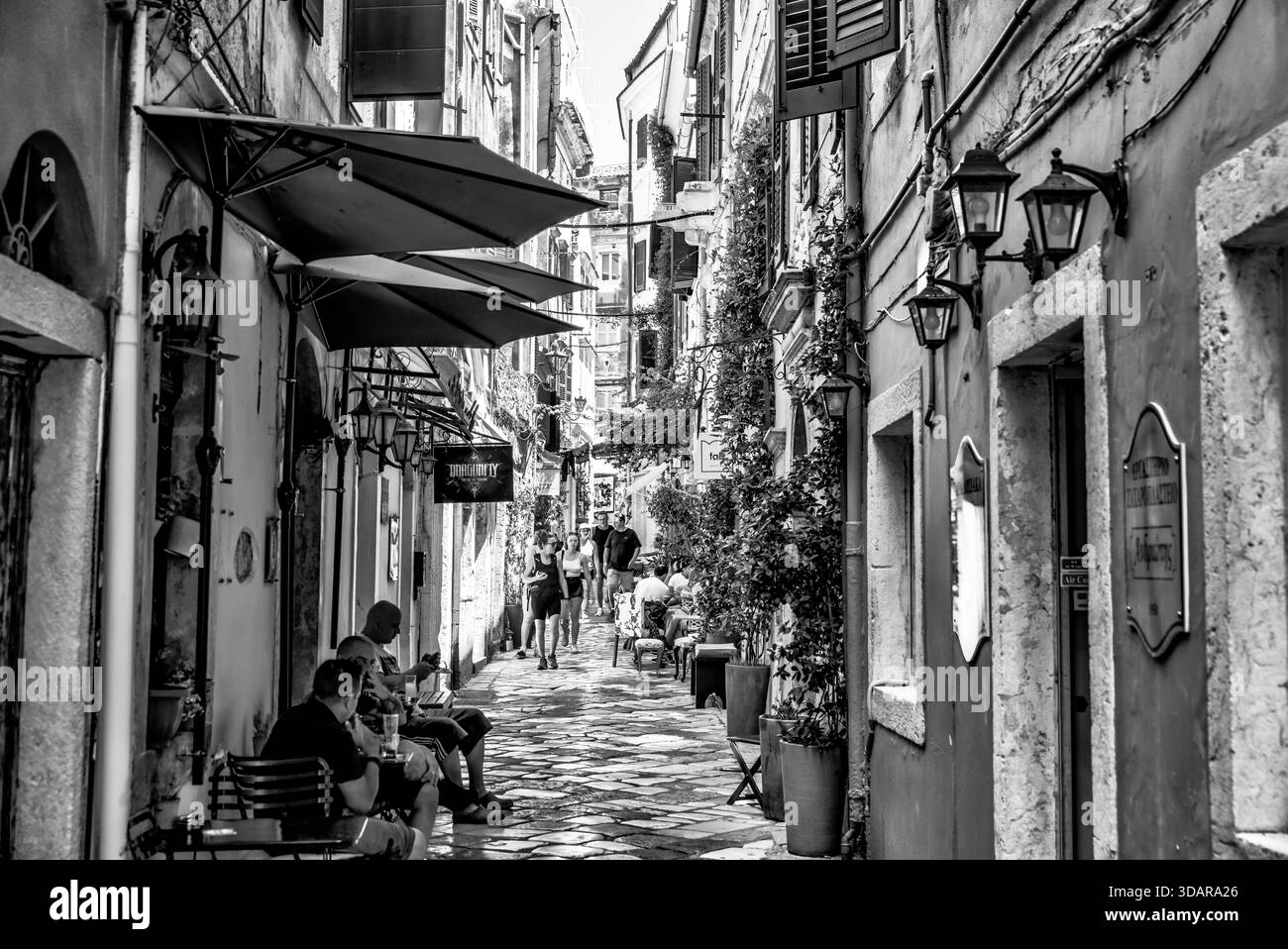 Vicolo in pietra fiancheggiato da caffetterie e residenze nella città vecchia di Corfù, Corfù, Grecia, che mostra un'intima scala di strade storiche. Foto Stock