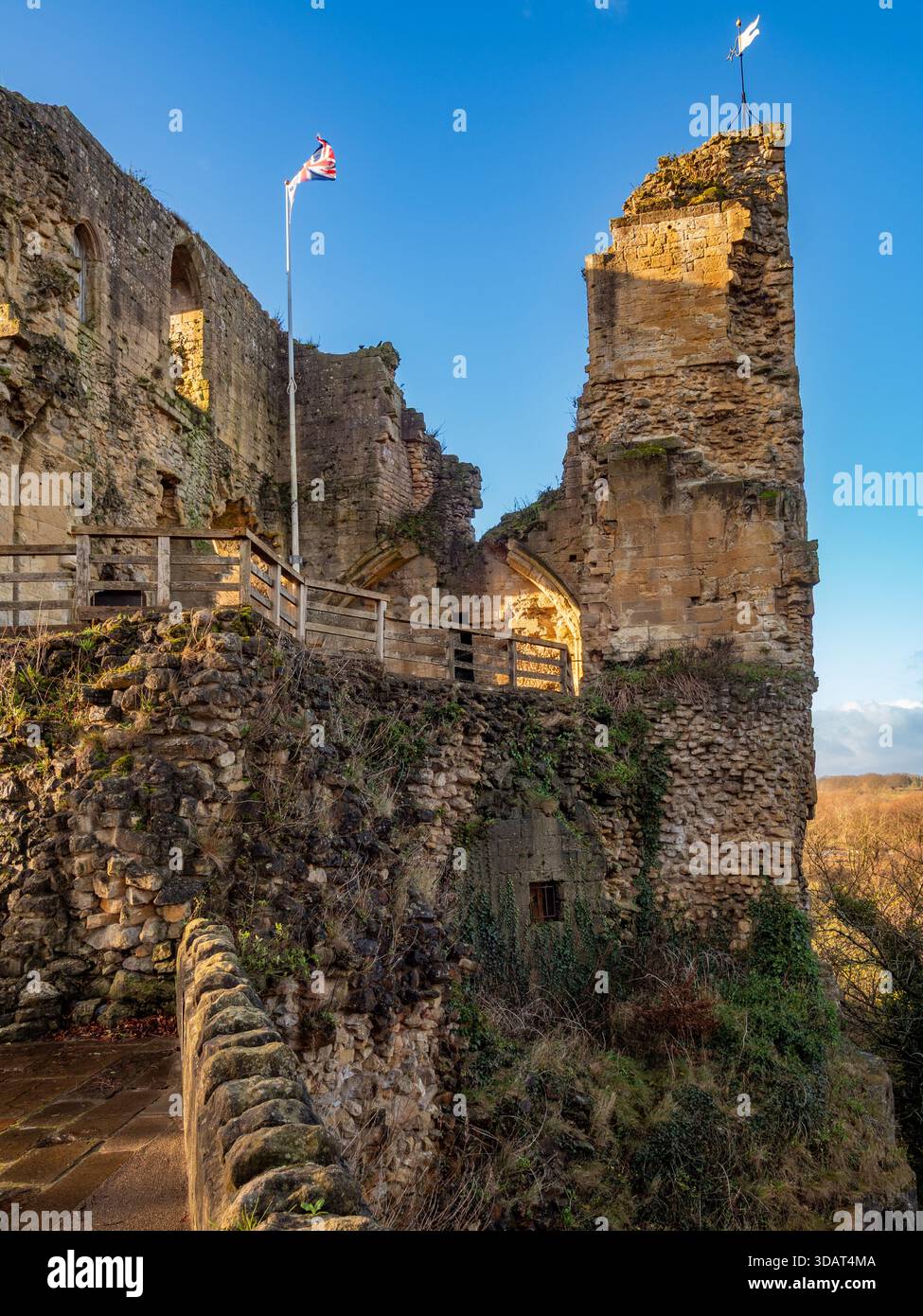 La bandiera Union Jack sventola sopra le pareti di pietra sbriciolate delle rovine medievali del castello di Knaresborough. Foto Stock