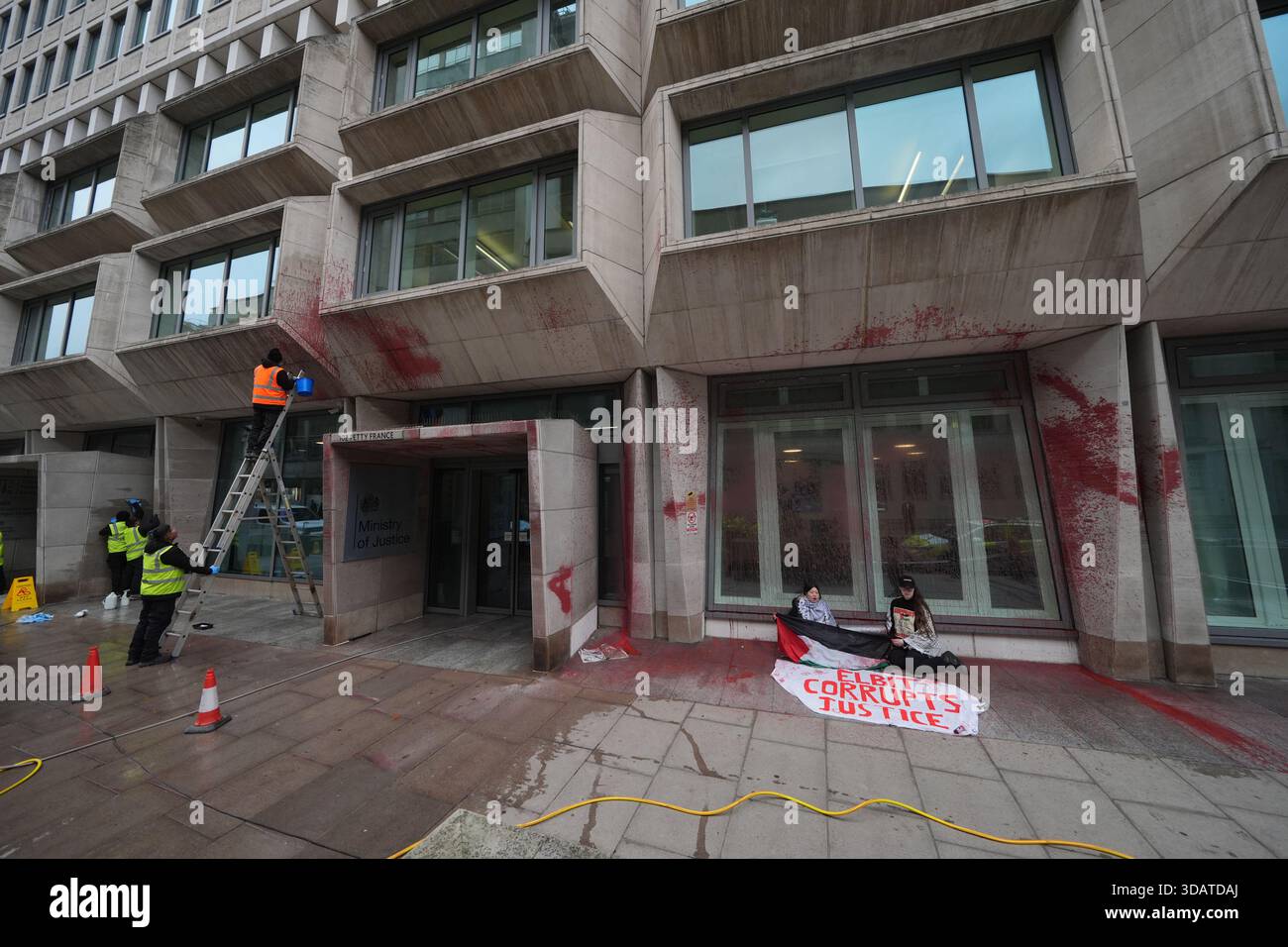I lavoratori che puliscono la vernice dall'esterno del Ministero della giustizia di Londra, dopo che i manifestanti di Palestine Action spruzzarono dipingevano l'edificio in vernice rossa. Data foto: Venerdì 12 dicembre 2025. Foto Stock
