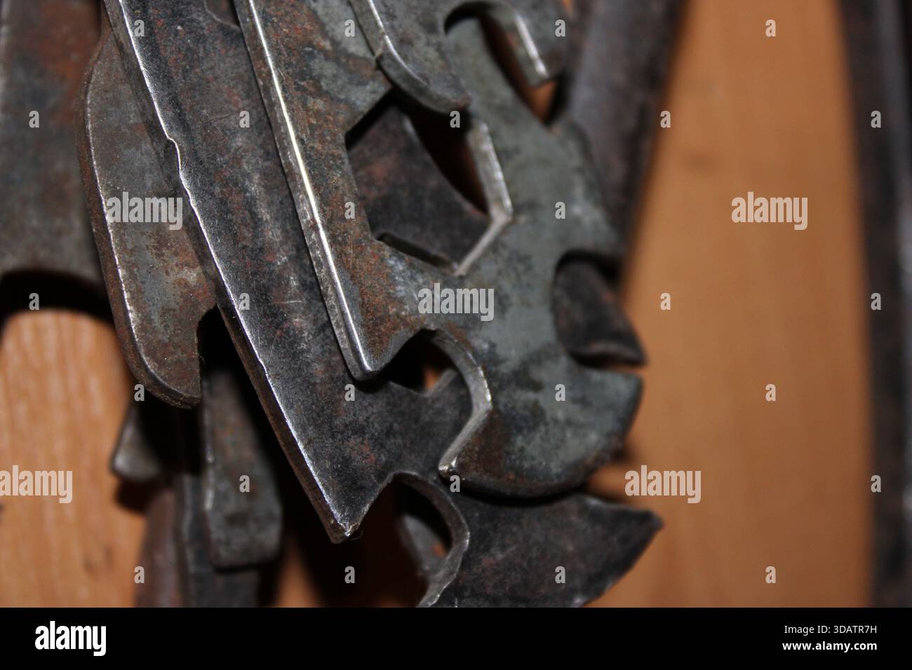 Diversi utensili metallici sono disposti su una parete di legno. Gli utensili mostrano segni di usura e sono utilizzati per attività quali riparazioni e lavorazione. Sono appesi in modo diverso Foto Stock