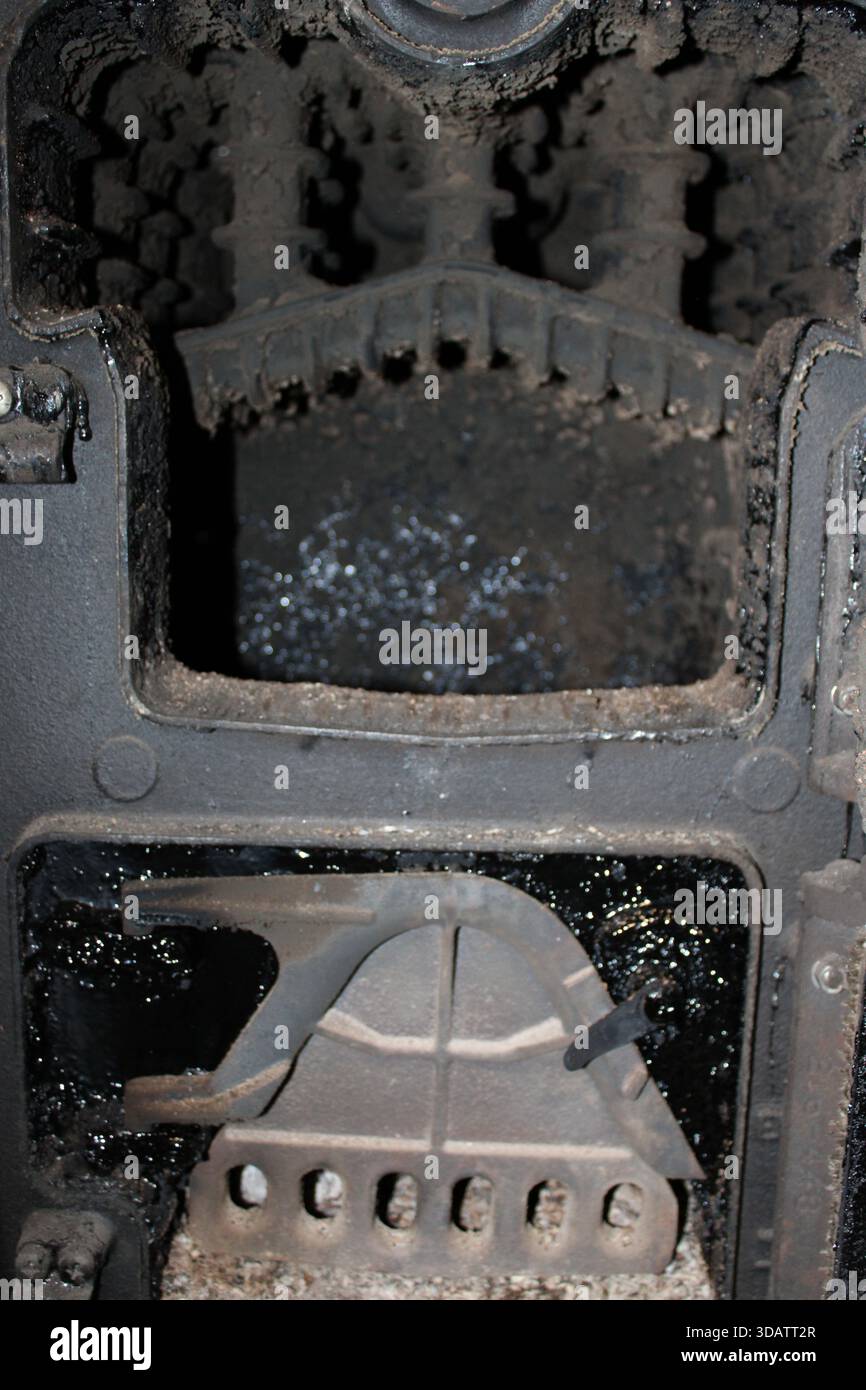 Una parte della macchina usurata si trova in un'officina meccanica. Residui e sporcizia coprono le superfici. L'area mostra segni di uso frequente e negligenza. Strumenti ed eq Foto Stock
