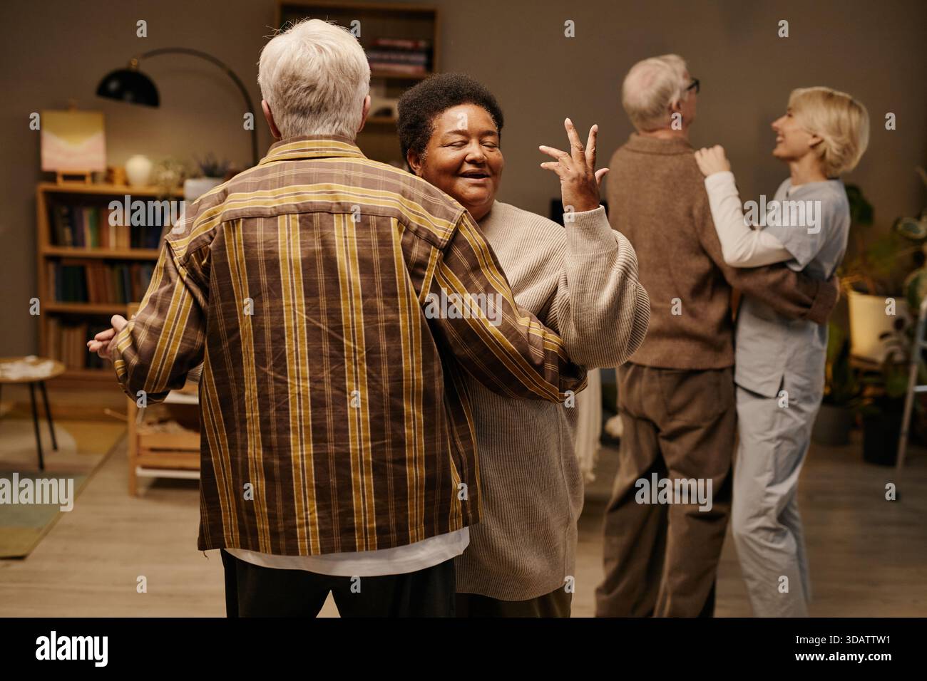 Donna nera anziana e uomo caucasico anziano che ballano gioiosamente nella casa di riposo Foto Stock