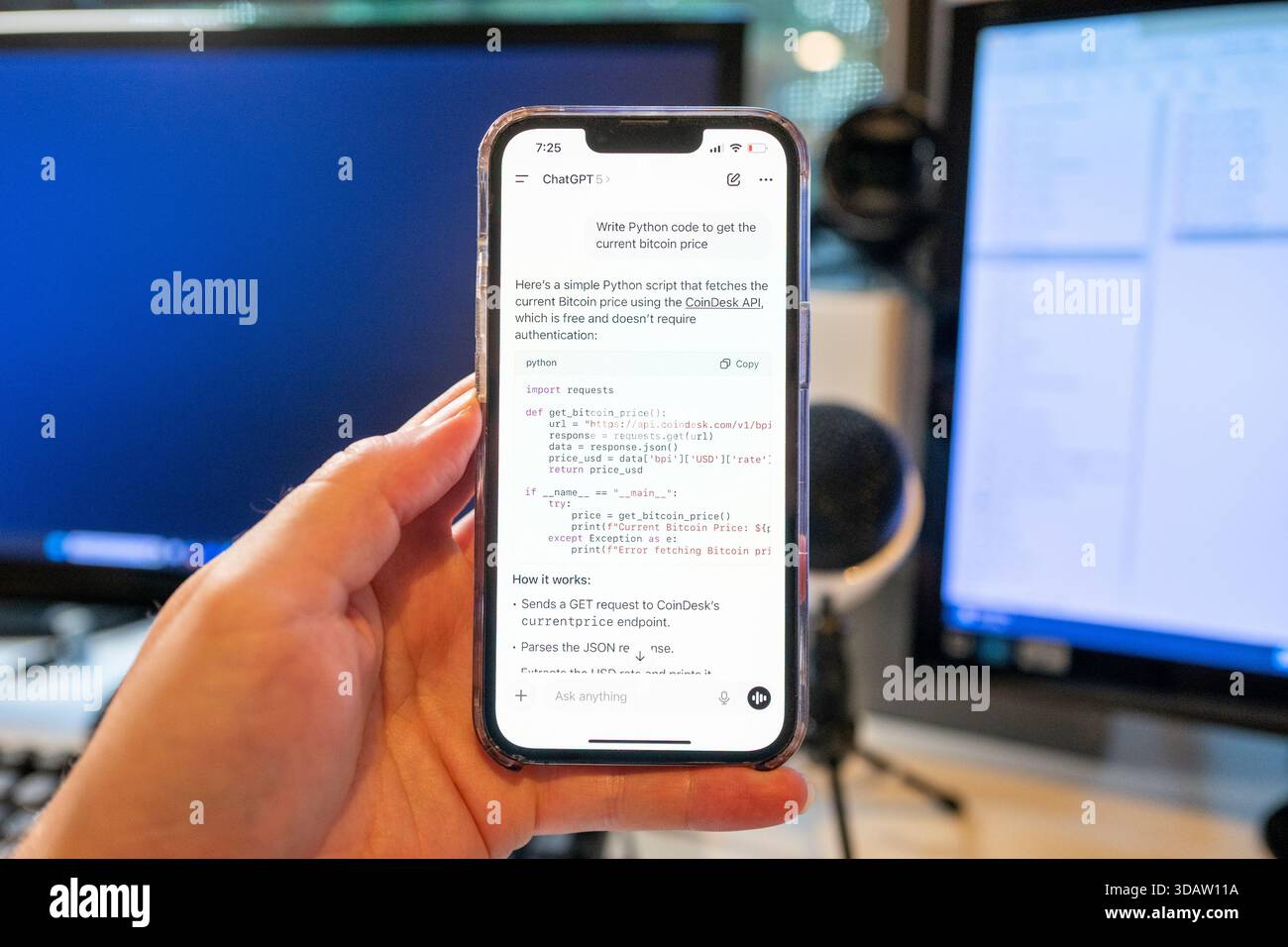 Immagine illustrativa della mano di una persona che tiene un iPhone e utilizza l'app OpenAI ChatGPT con il modello GPT-5 per scrivere codice software Python, con schermi per computer e attrezzature per ufficio sullo sfondo, Lafayette, California, 7 agosto 2025. (Foto di Smith Collection/Gado/Sipa USA) Foto Stock