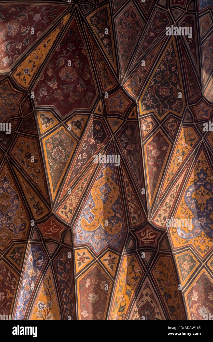 Vista di un soffitto decorato con motivi geometrici e disegni floreali in tonalità calde, che creano un ipnotico arazzo visivo, Lahore, Punjab, Foto Stock