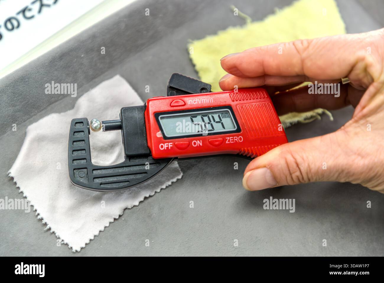 Una perla trovata viene misurata con un calibro digitale durante la "raccolta di perle" a Shinju no Sato. Foto Stock