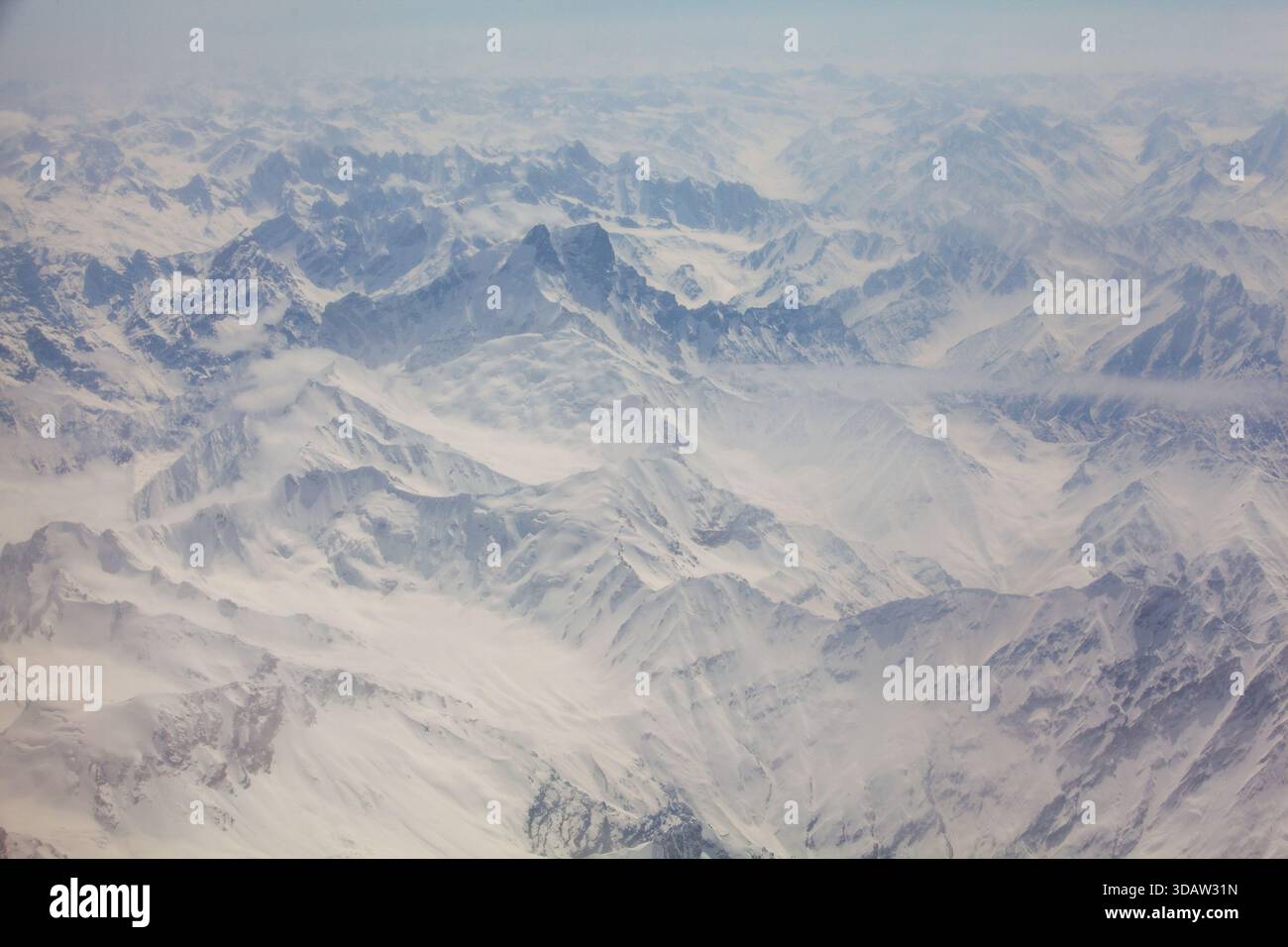 La vista aerea delle vette innevate e delle valli crea uno splendido arazzo bianco e grigio, che mette in risalto la bellezza aspra del terreno montuoso, Foto Stock