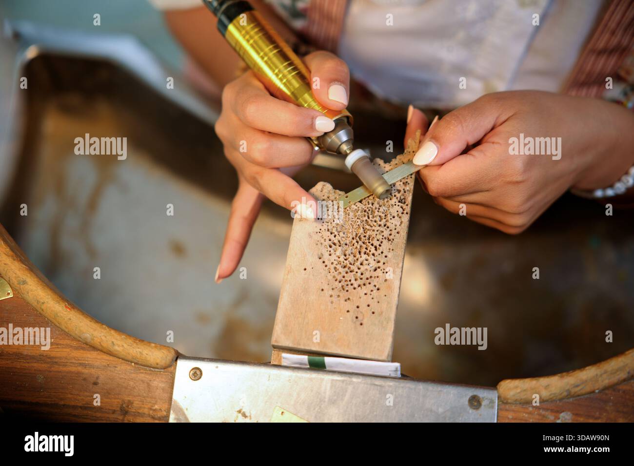 Un'abile artigiana realizza meticolosamente un complesso gioiello, mettendo in mostra la sua esperienza e la sua attenzione ai dettagli. Le sue mani lavorano delicatamente Foto Stock