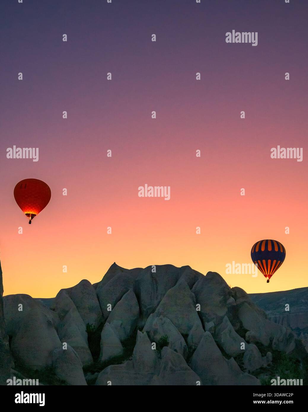 Splendida vista delle mongolfiere che si innalzano sul paesaggio roccioso della Cappadocia, Turchia, all'alba. I colori vivaci illuminano il cielo, creando Foto Stock