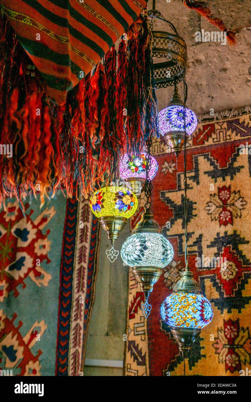 Le lampade a sospensione ornate illuminano con vivaci motivi a mosaico sopra tappeti e arazzi colorati. Questa scena del mercato cattura il ricco patrimonio culturale di Cap Foto Stock