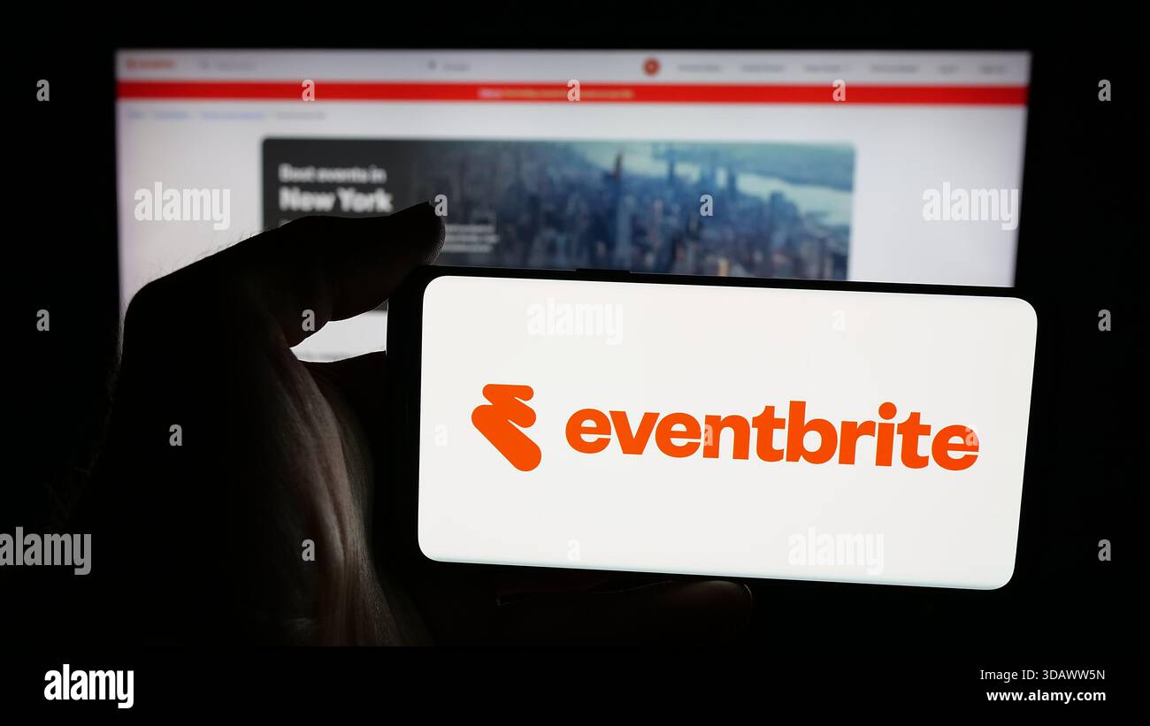 Stoccarda, Germania - 11-30-2025: Persona che detiene un telefono cellulare con il logo della società americana di pianificazione eventi Eventbrite Inc. Sullo schermo davanti alla pagina web. Foto Stock
