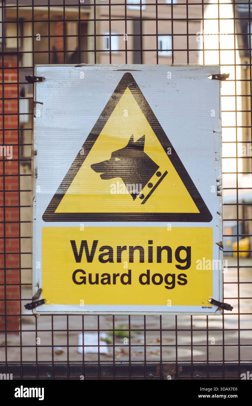 Un cartello giallo "Warning Guard Dogs" su un cancello Foto Stock