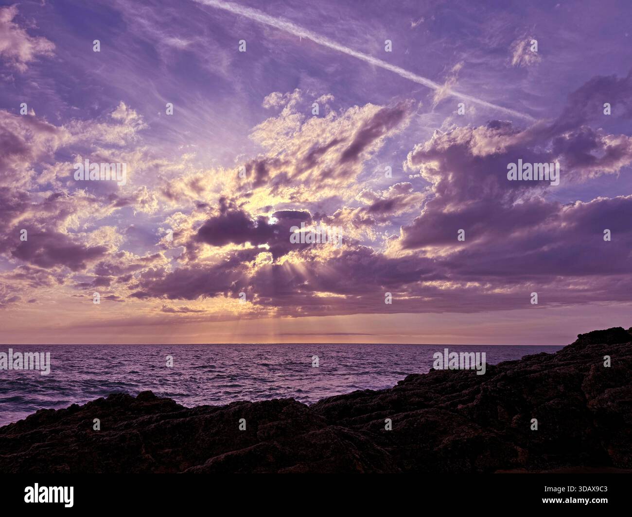 Nuvole al tramonto sull'oceano scuro e sulla costa rocciosa Foto Stock