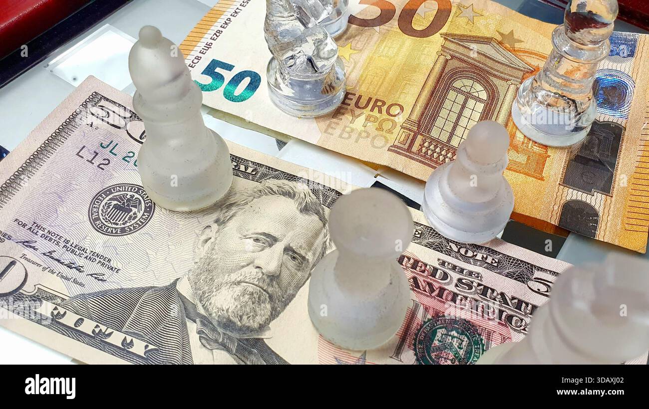 Due banconote da 50 dollari USA e 50 euro di fronte a una scacchiera, in un gioco di supremazia e guerra tariffaria commerciale. Foto Stock