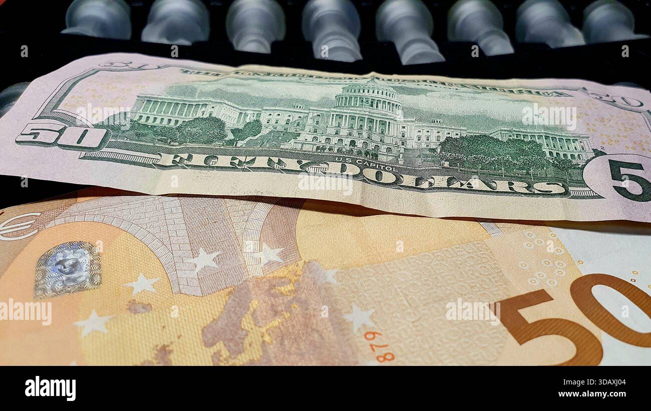 Due banconote da 50 dollari USA e 50 euro di fronte a una scacchiera, in un gioco di supremazia e guerra tariffaria commerciale. Foto Stock
